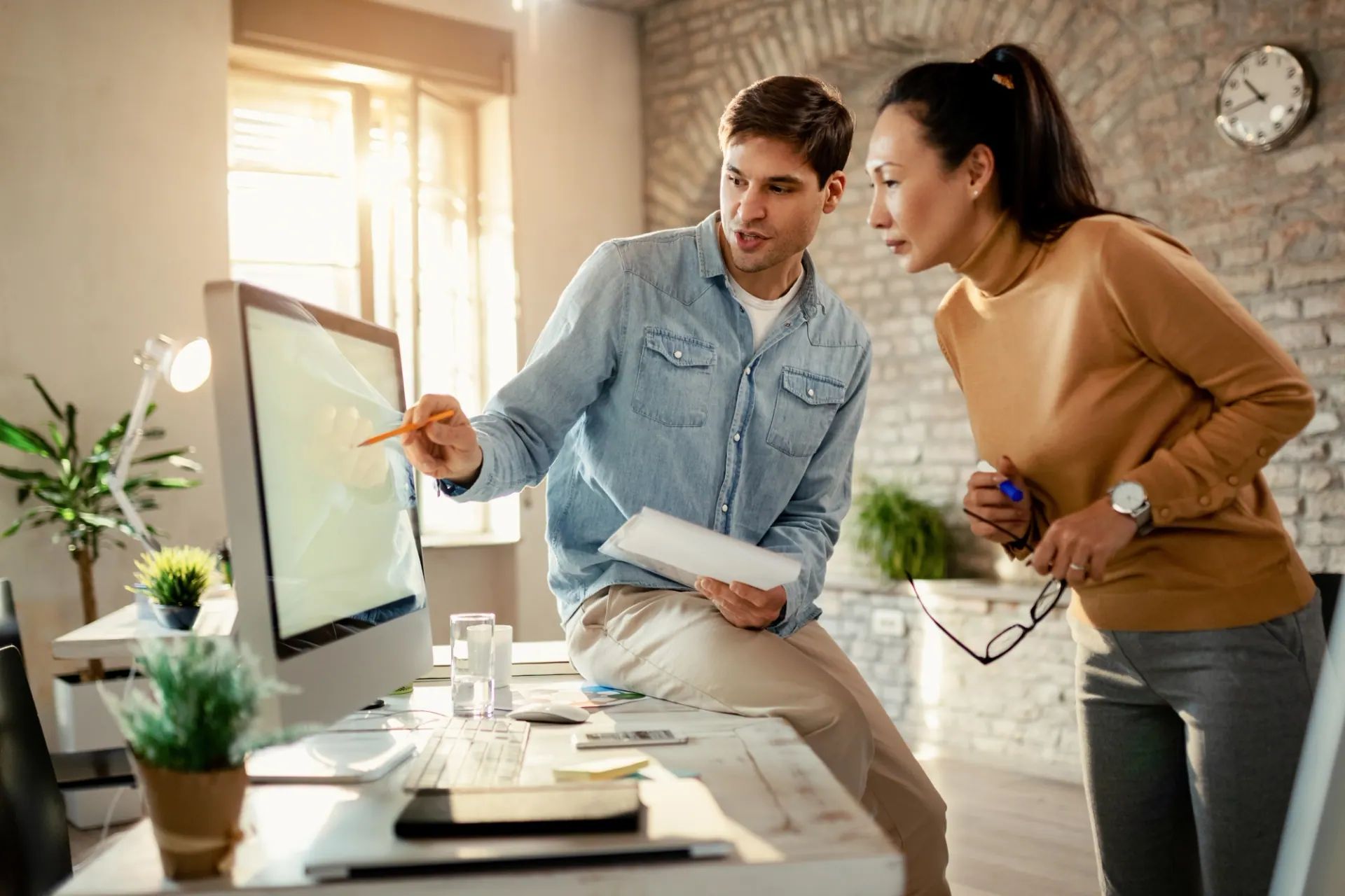 Two people reviewing design plans together at a computer