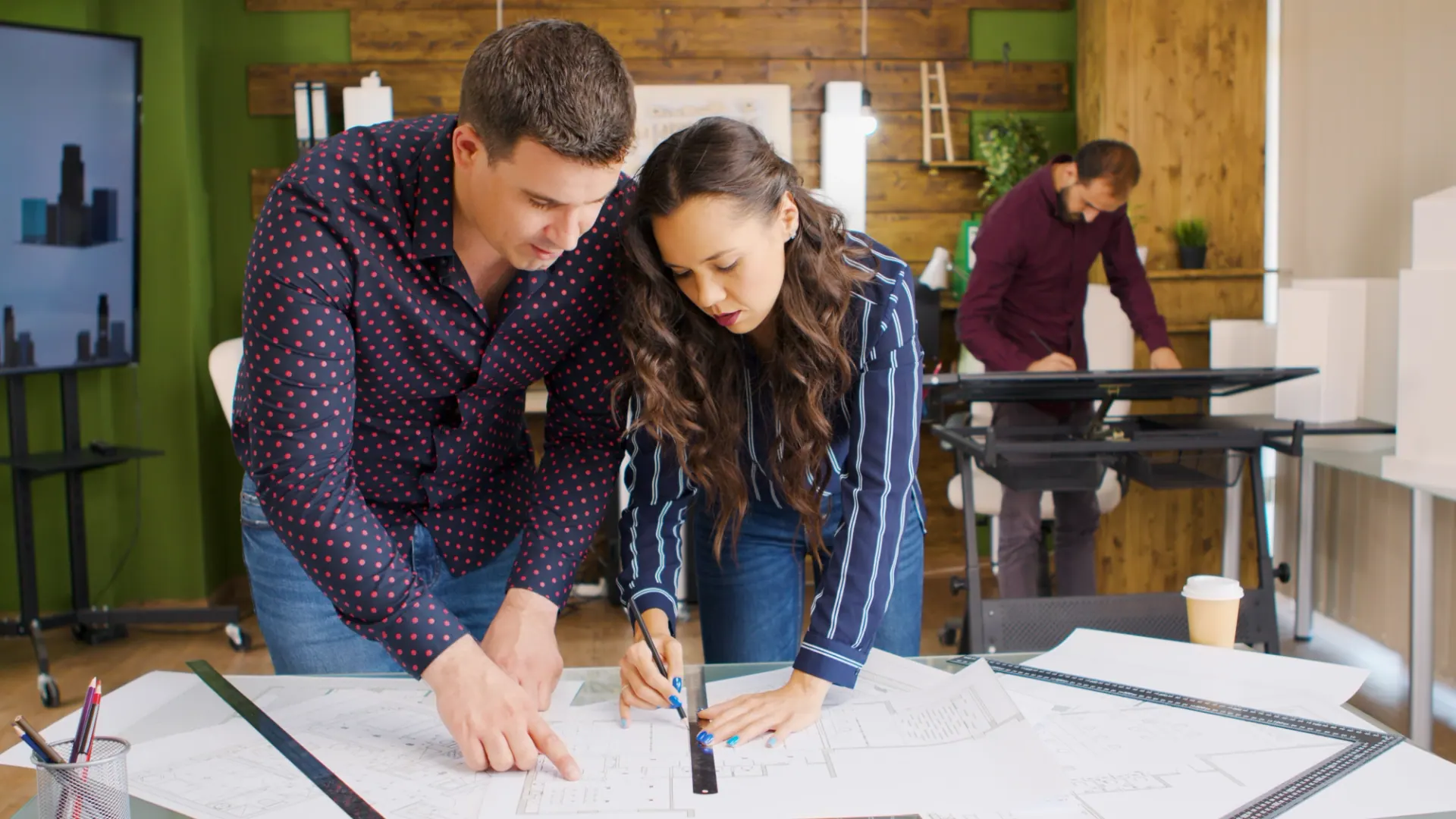 Two designers sketching renovation plans on drawings at a studio table