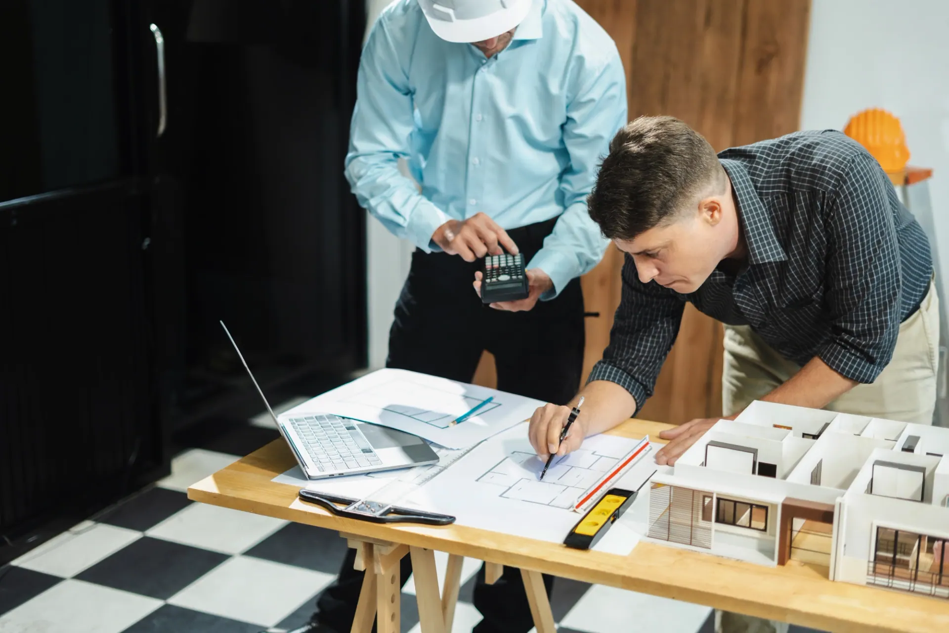 Construction drawings, a scale model and a calculator on a planning table