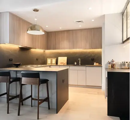 Wood-grain kitchen cabinetry with a dark backsplash and under-cabinet lighting