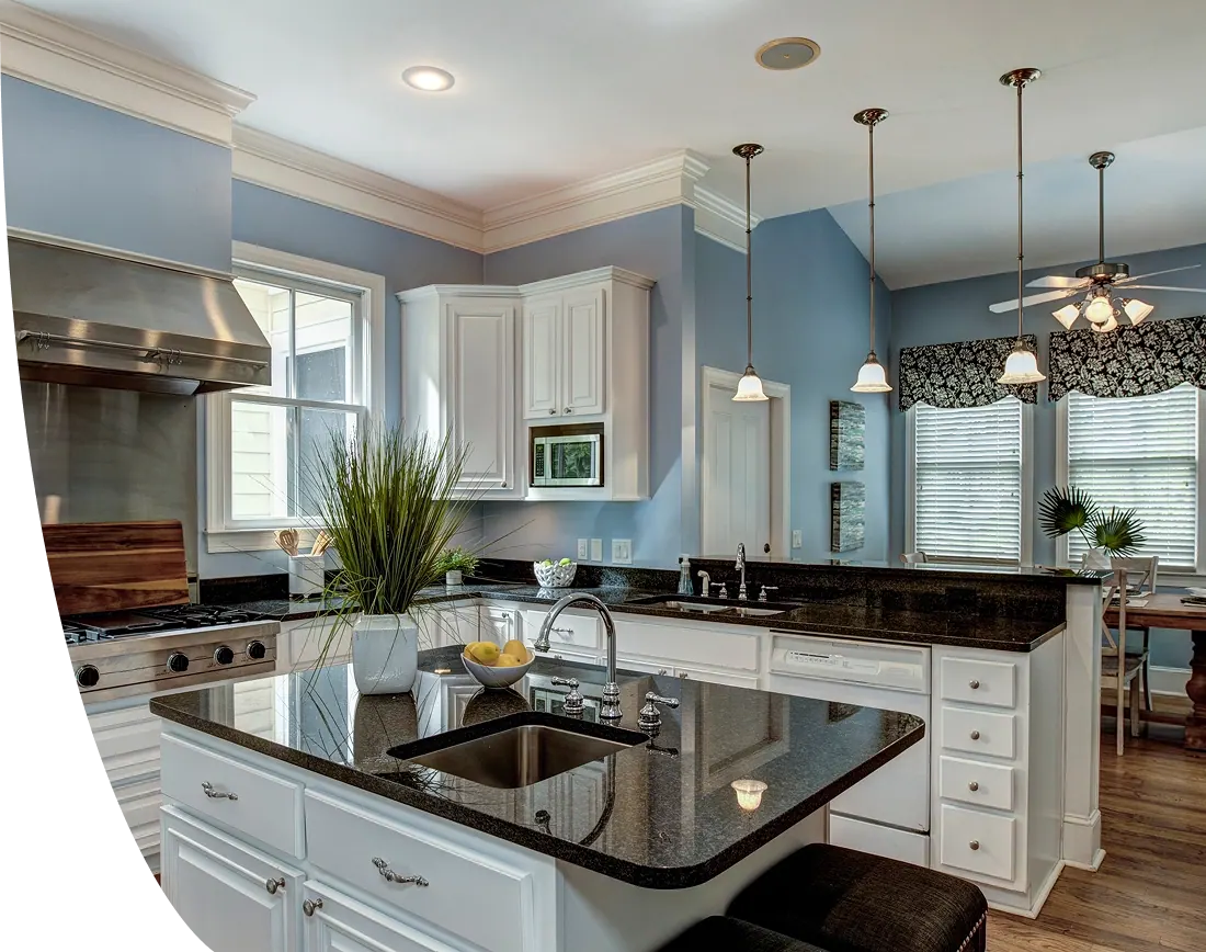 Kitchen with an island sink, dark countertops, white cabinetry and pendant lights